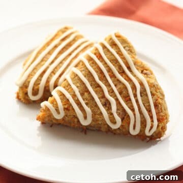 Two keto carrot cake scones on a white plate over an orange napkin.