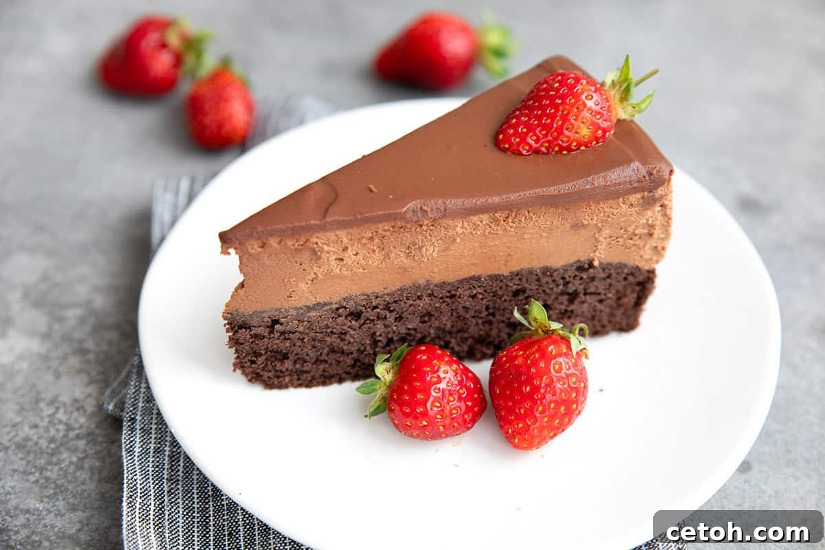 Close up shot of a slice of keto chocolate mousse cake on a white plate with fresh strawberries.