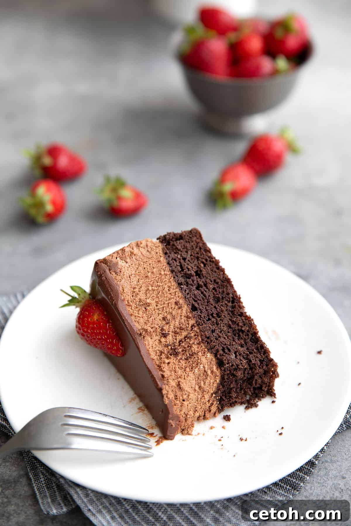 A slice of Keto Chocolate Mousse Cake on its side, on a white plate, with a forkful taken out of it.