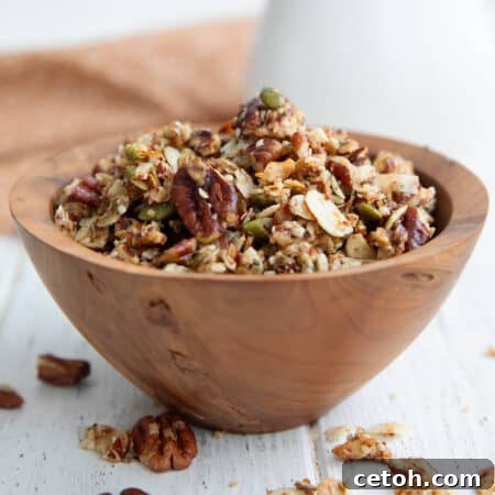 Low-Carb Keto Granola Recipe for Air Fryer (Crunchy & Fast) 15 Keto Air Fryer Granola piled up in a wooden bowl on a white wooden table.