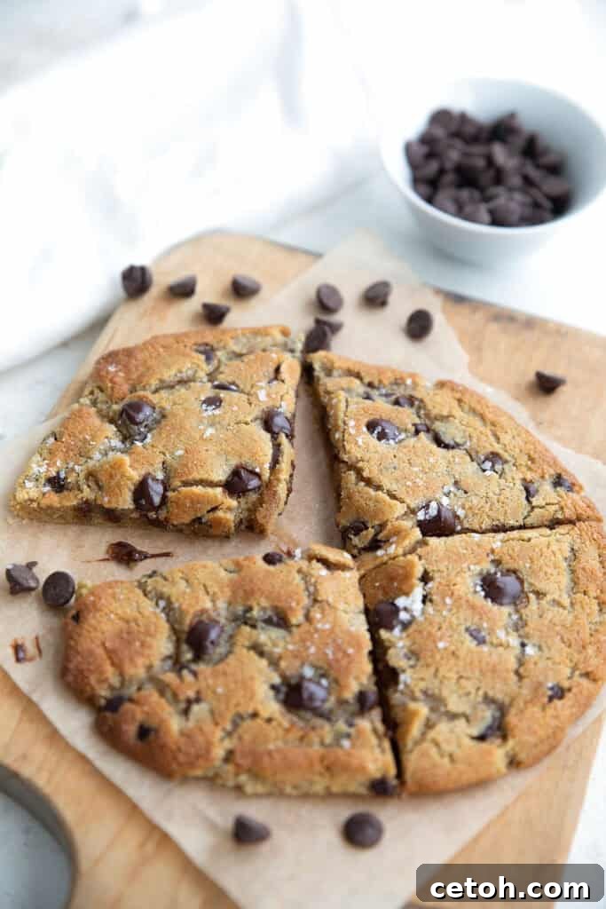 Low-Carb Keto Granola Recipe for Air Fryer (Crunchy & Fast) 10 A large keto chocolate chip cookie cut into four pieces, sitting on a wooden cutting board with chocolate chips strewn around.