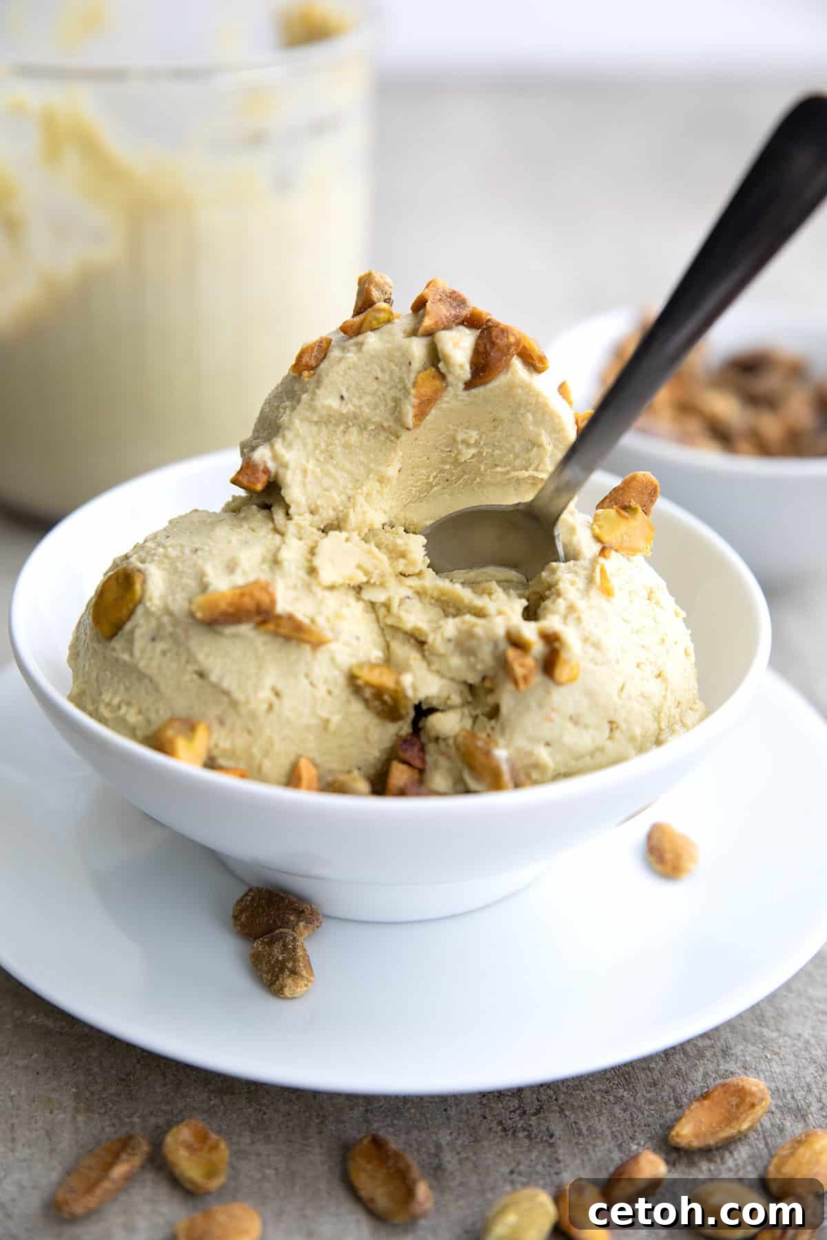 A white bowl with three scoops of keto pistachio ice cream, with a spoon digging into it.