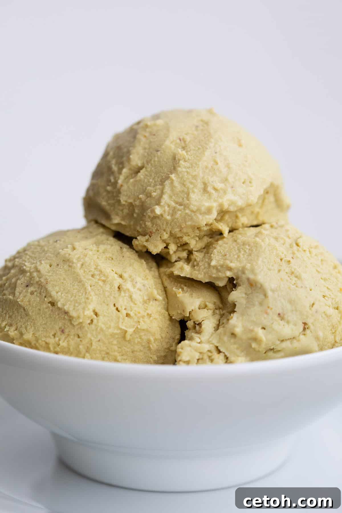 Close up shot of a white bowl with three scoops of keto pistachio ice cream.