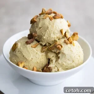 A white bowl with three scoops of keto pistachio ice cream, topped with chopped, salted pistachios.