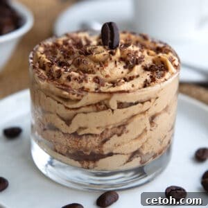 Tiramisu Protein Mousse Recipe 3 Close up shot of Tiramisu Protein Mousse in a glass dessert dish with chocolate shavings and an espresso bean on top.