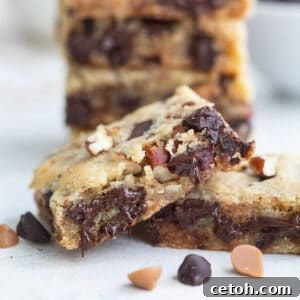 Close up shot of a keto cookie bar with melty chocolate chips and chopped pecans.