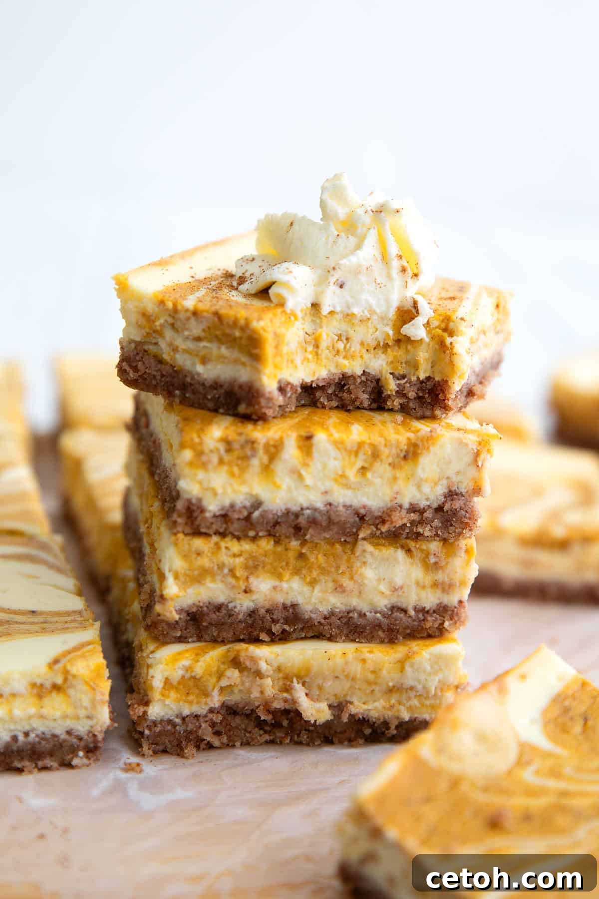 Keto Pumpkin Swirl Cheesecake Bars 5 a stack of keto pumpkin cheesecake bars with a bite taken out of the top one.