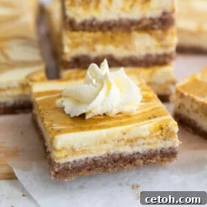 Keto Pumpkin Swirl Cheesecake Bars 8 Close up shot of a keto pumpkin swirl cheesecake bar with a dollop of whipped cream on top.